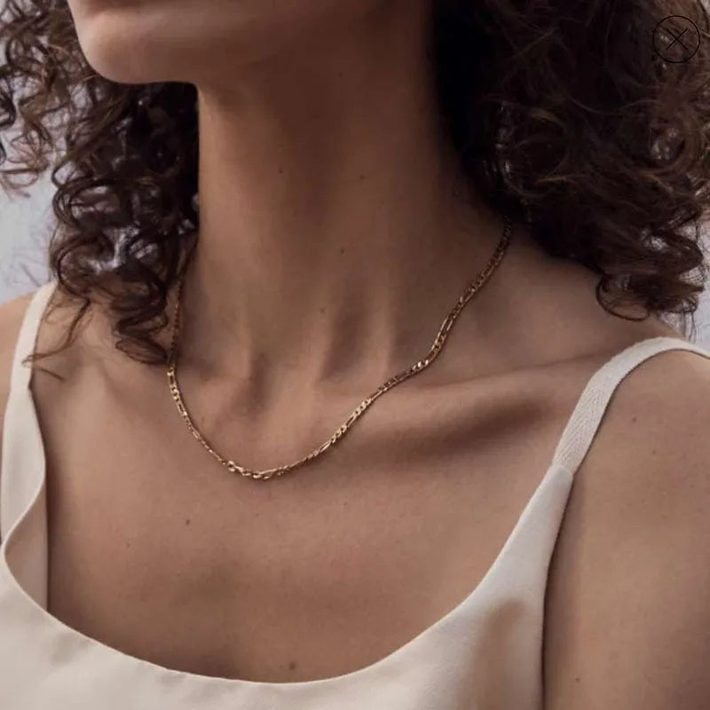 Close-up of a person wearing a gold necklace with a plain background