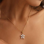 Gold necklace with a flower-shaped pendant worn by a person