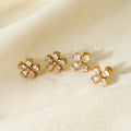 Set of gold and crystal flower-shaped earrings on a beige fabric background