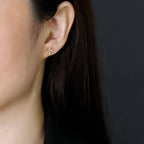 Close-up of a person wearing a floral earring against a dark background