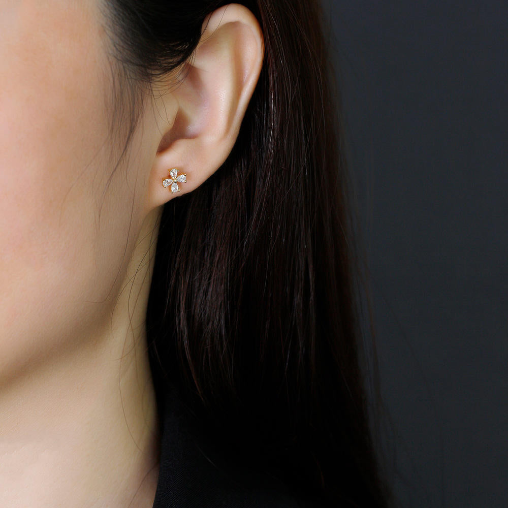 Close-up of a person wearing a floral earring against a dark background