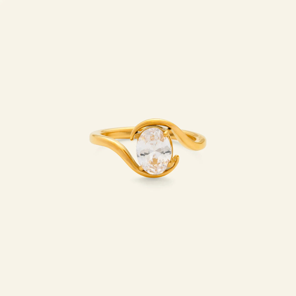 Gold ring with a clear gemstone on a beige background