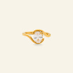 Gold ring with a clear gemstone on a beige background