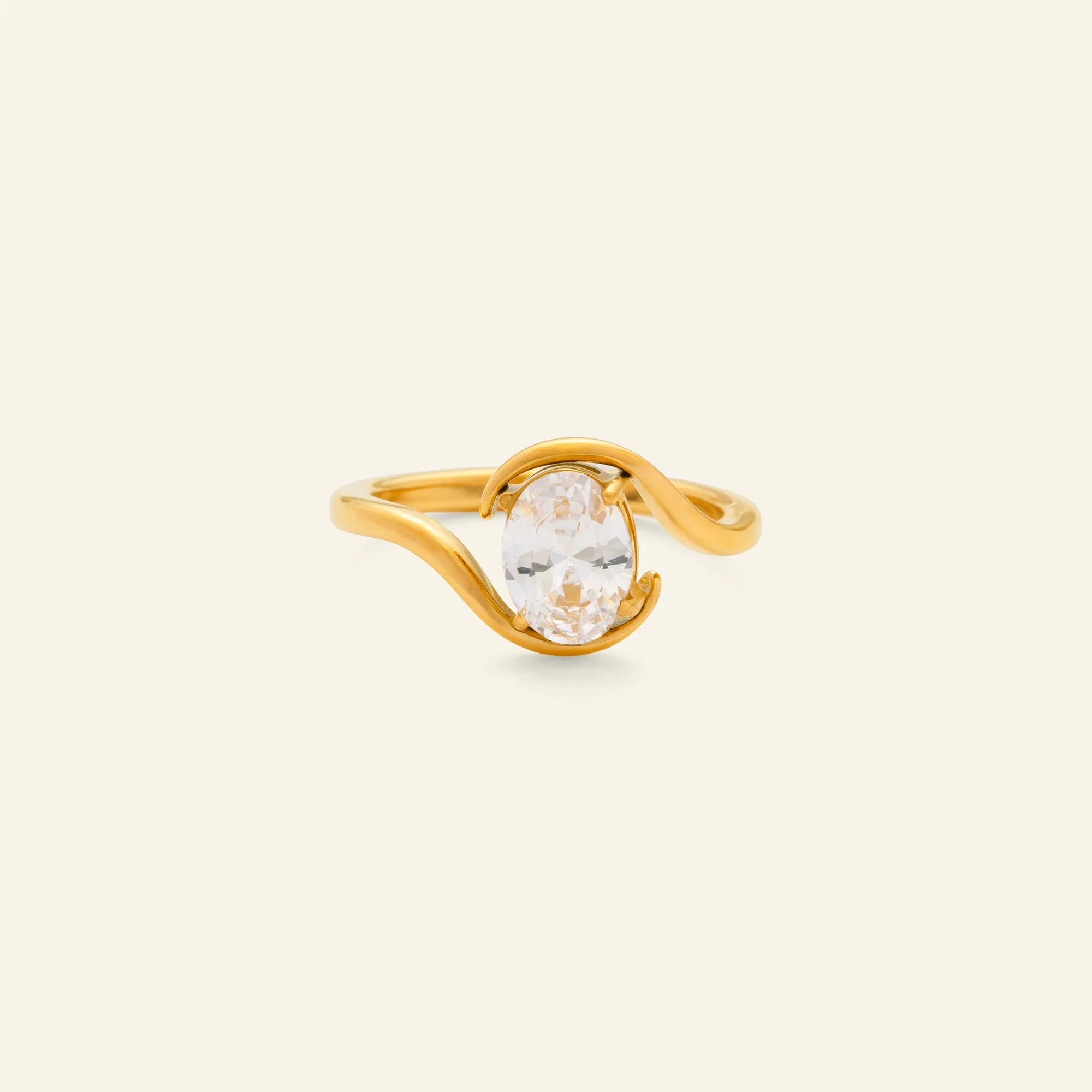 Gold ring with a clear gemstone on a beige background