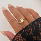 Gold ring with a diamond on a hand wearing a black lace sleeve against a white background
