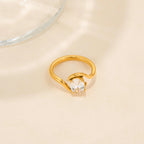 Gold ring with a clear gemstone on a beige surface