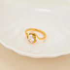 Gold ring with a clear gemstone on a white dish