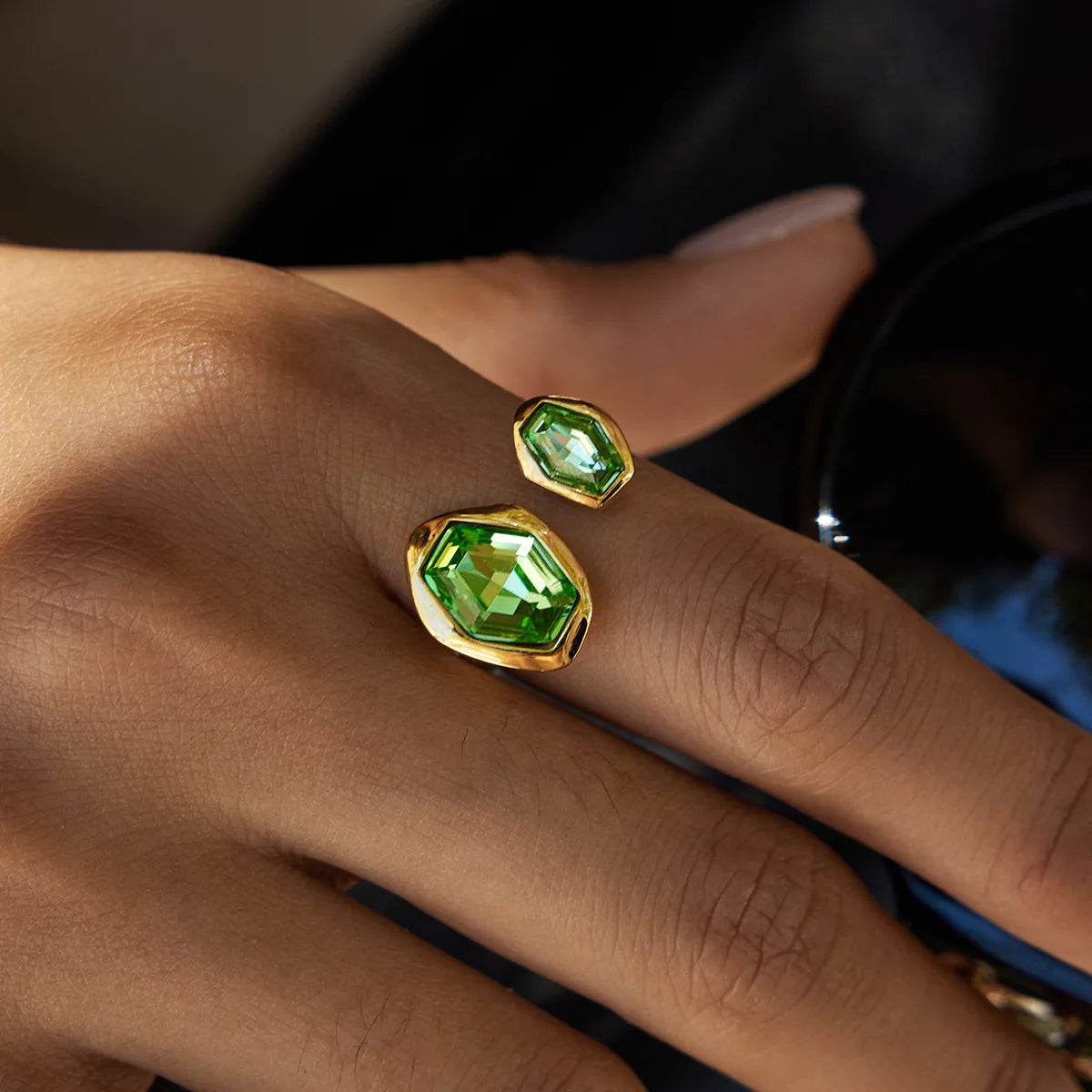 Gold rings with green gemstones on a person's fingers