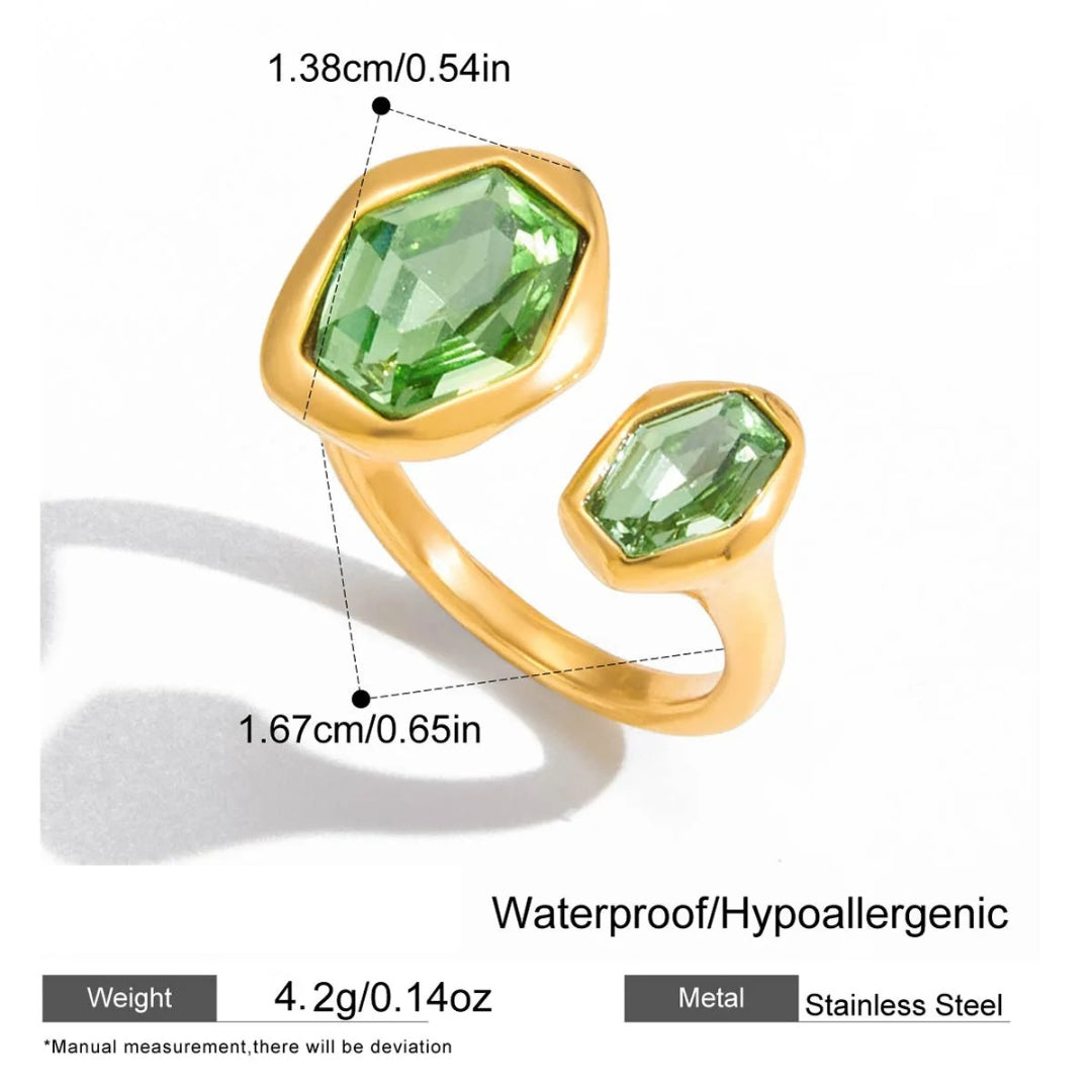 Gold ring with green gemstones and measurements on a white background