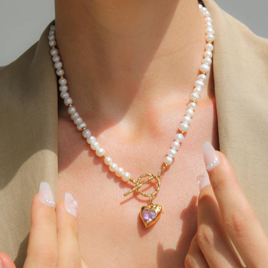 Pearl necklace with a gold clasp worn by a person, with a neutral background