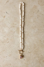 Pearl necklace with a heart-shaped pendant on a beige surface