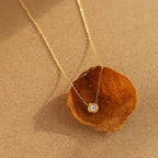 Gold necklace with a pendant on a brown leaf