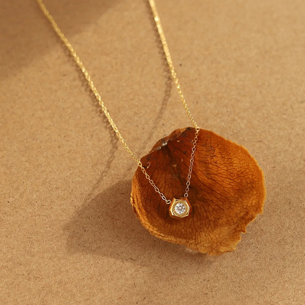 Gold necklace with a pendant on a brown leaf