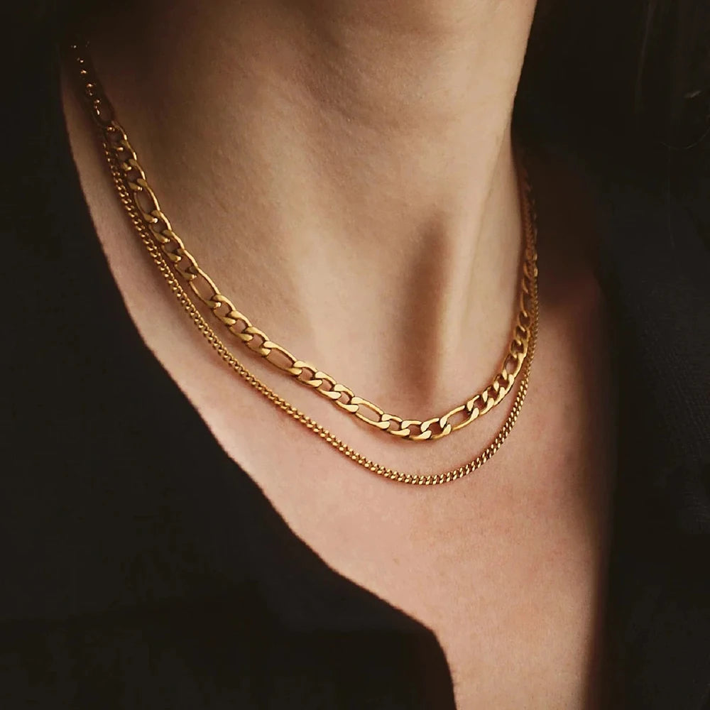 Gold chain necklace on a person against a dark background