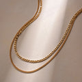 Two gold chain necklaces on a light beige background