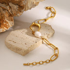 Gold chain necklace with a pearl pendant on a stone surface