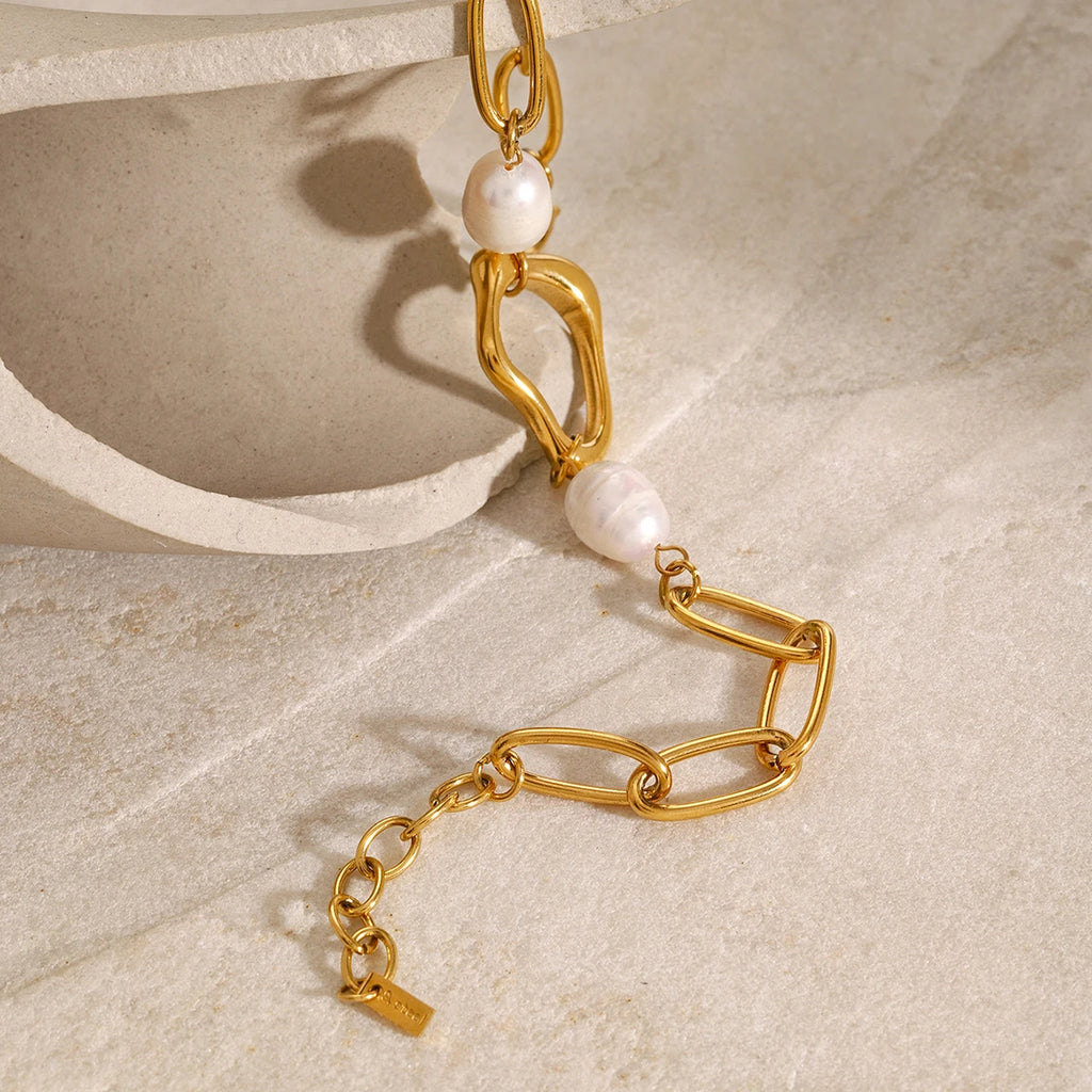 Gold bracelet with pearls on a beige stone surface