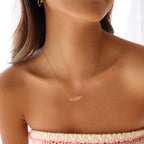 Gold necklace with a pendant on a person wearing a strapless top.