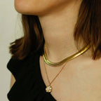Close-up of a person wearing a gold necklace with a pendant.