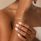 Gold bracelet on a wrist with a neutral background