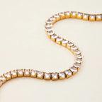 Gold bracelet with clear gemstones on a light beige background