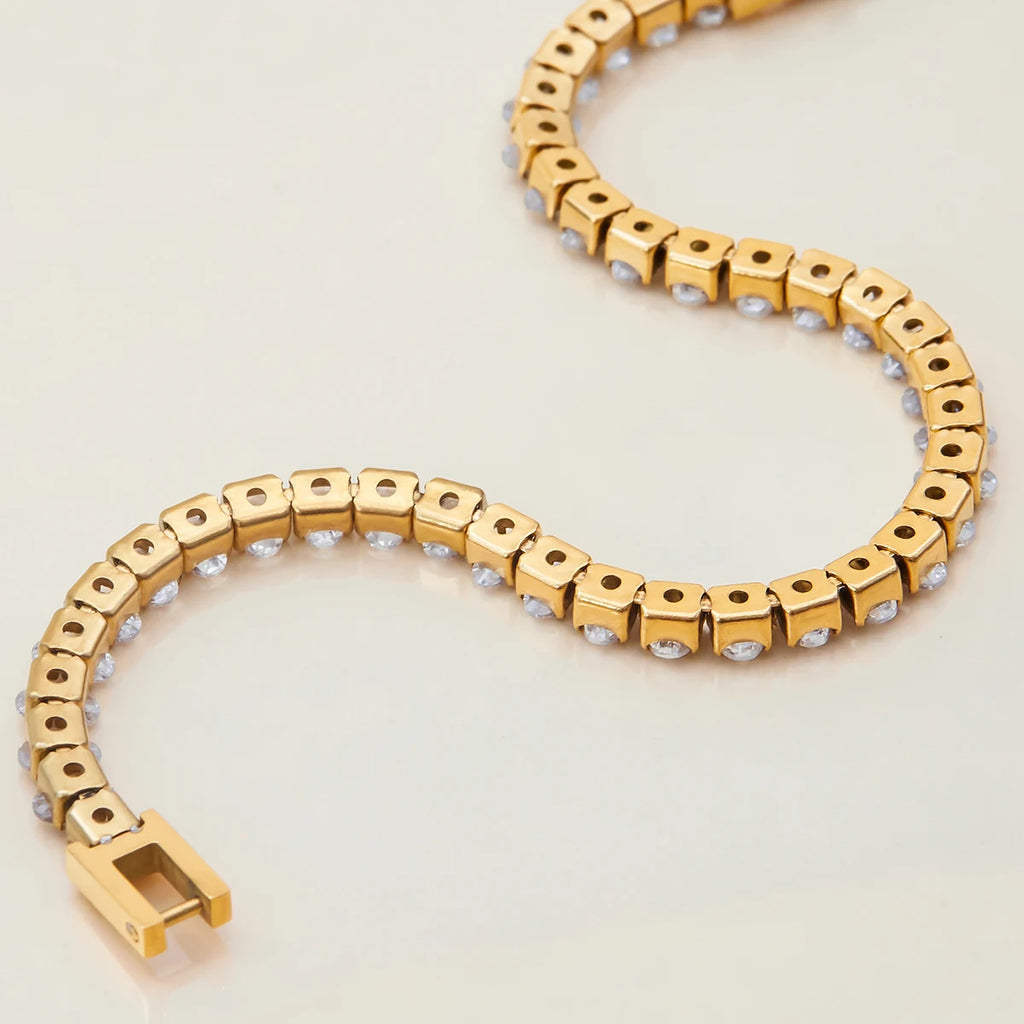 Gold bracelet with small stones on a light beige background