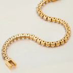 Gold bracelet with small stones on a light beige background