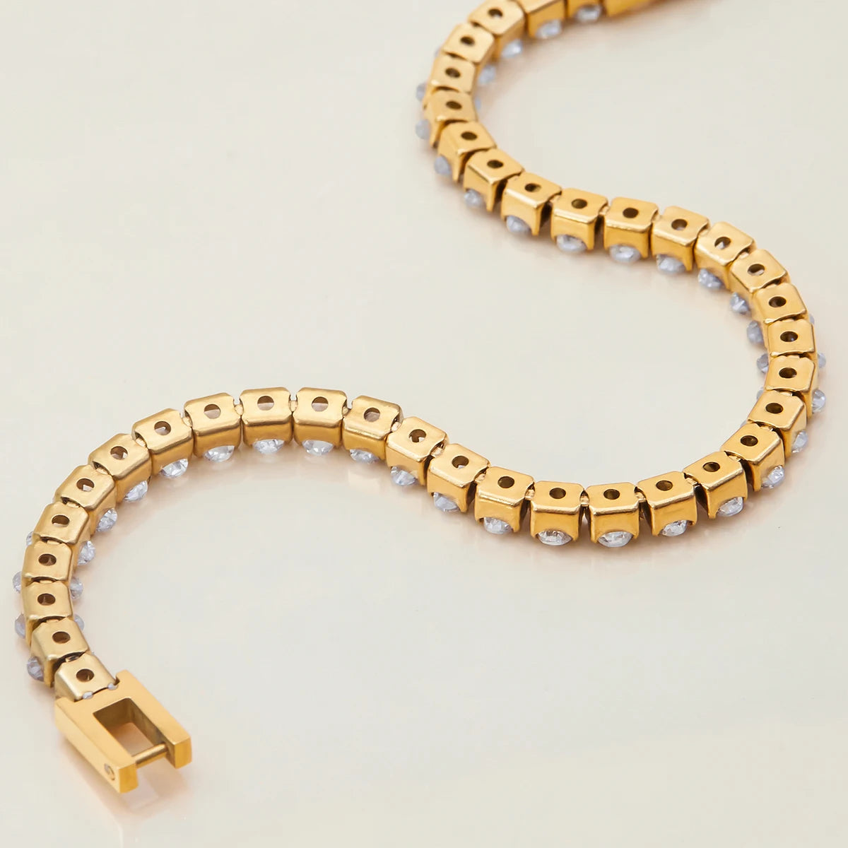 Gold bracelet with small stones on a light beige background