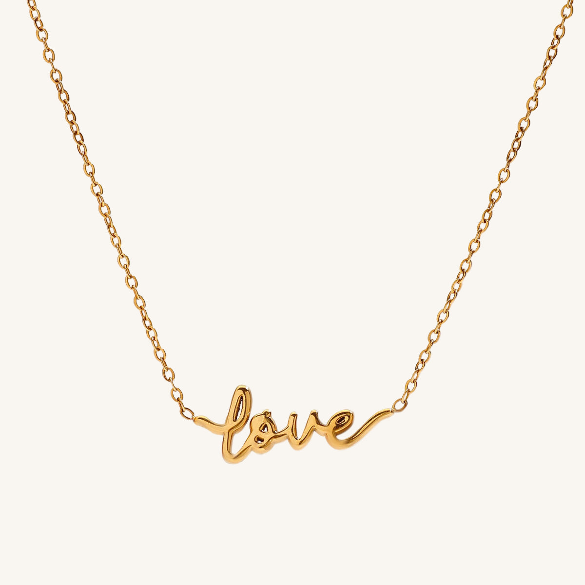 Gold necklace with 'love' pendant on a white background
