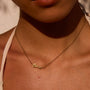 Gold 'love' necklace on a person's neck with a neutral background