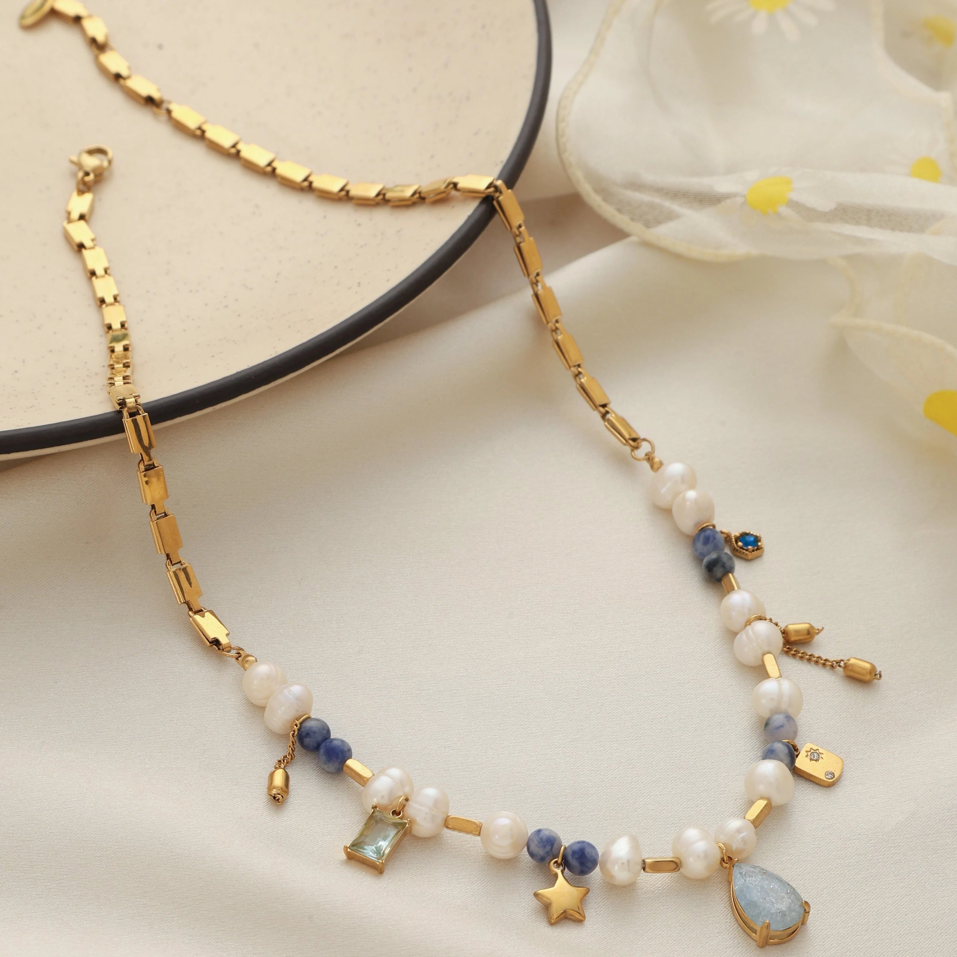 Gold necklace with pearls and gemstones on a light background