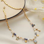 Gold necklace with pearls and gemstones on a light background