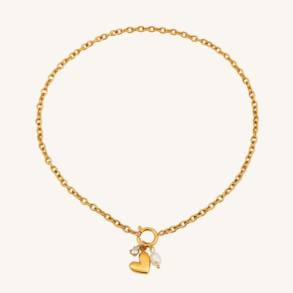 Gold bracelet with heart and pearl charm on a white background