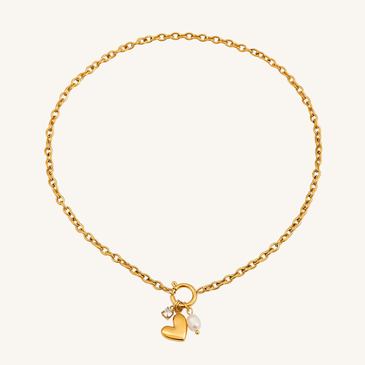 Gold bracelet with heart and pearl charm on a white background