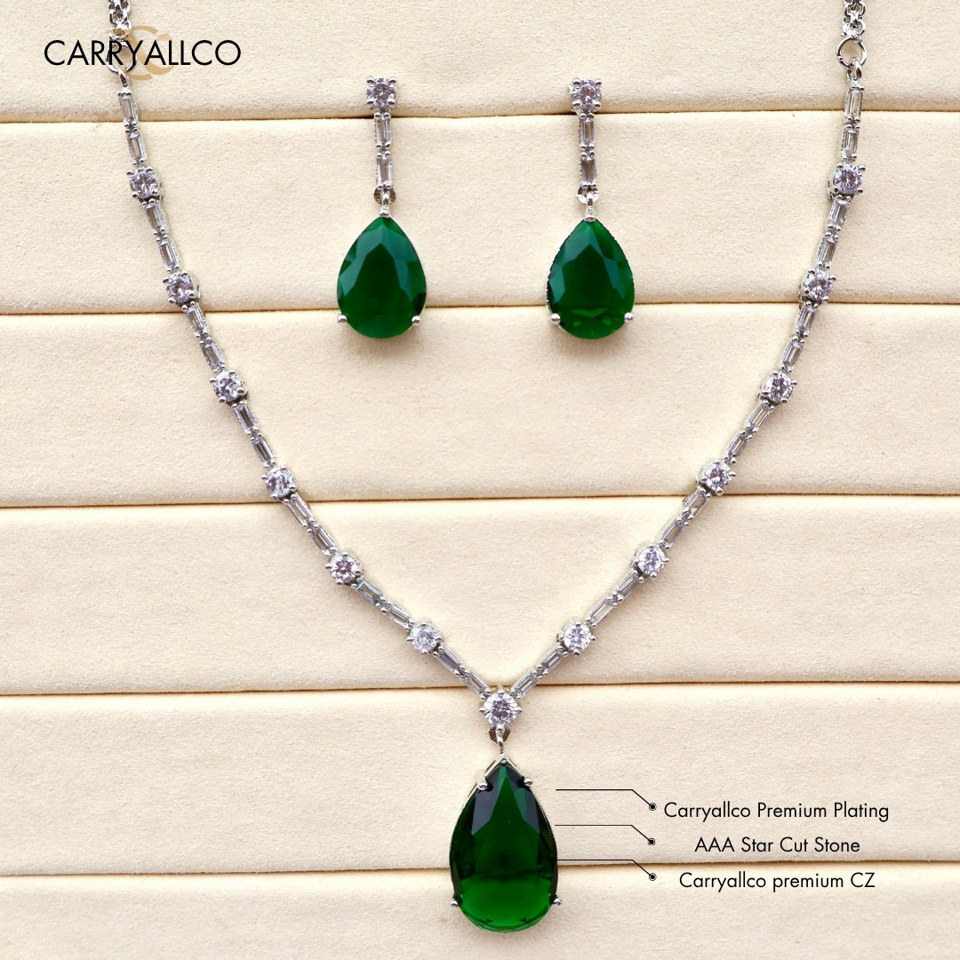 Jewelry set with green teardrop pendants and chain on a wooden surface, featuring Carryllco branding.