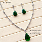 Jewelry set with green teardrop pendants and silver chain on a light wood background, featuring Carryalico branding.