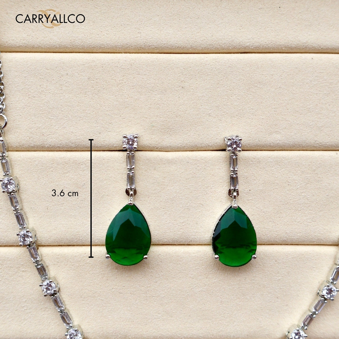 Green teardrop earrings with silver accents on a wooden surface, featuring the brand 'CARRYALLCO'.