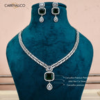 Jewelry set with necklace and earrings featuring green stones and silver plating on a wooden surface.