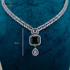 Necklace with green gemstone and silver chain on a wooden surface, featuring the brand 'CARRYALLCO'.