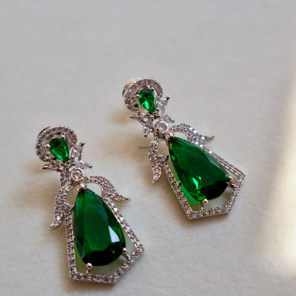 Pair of green teardrop earrings with silver accents on a light background