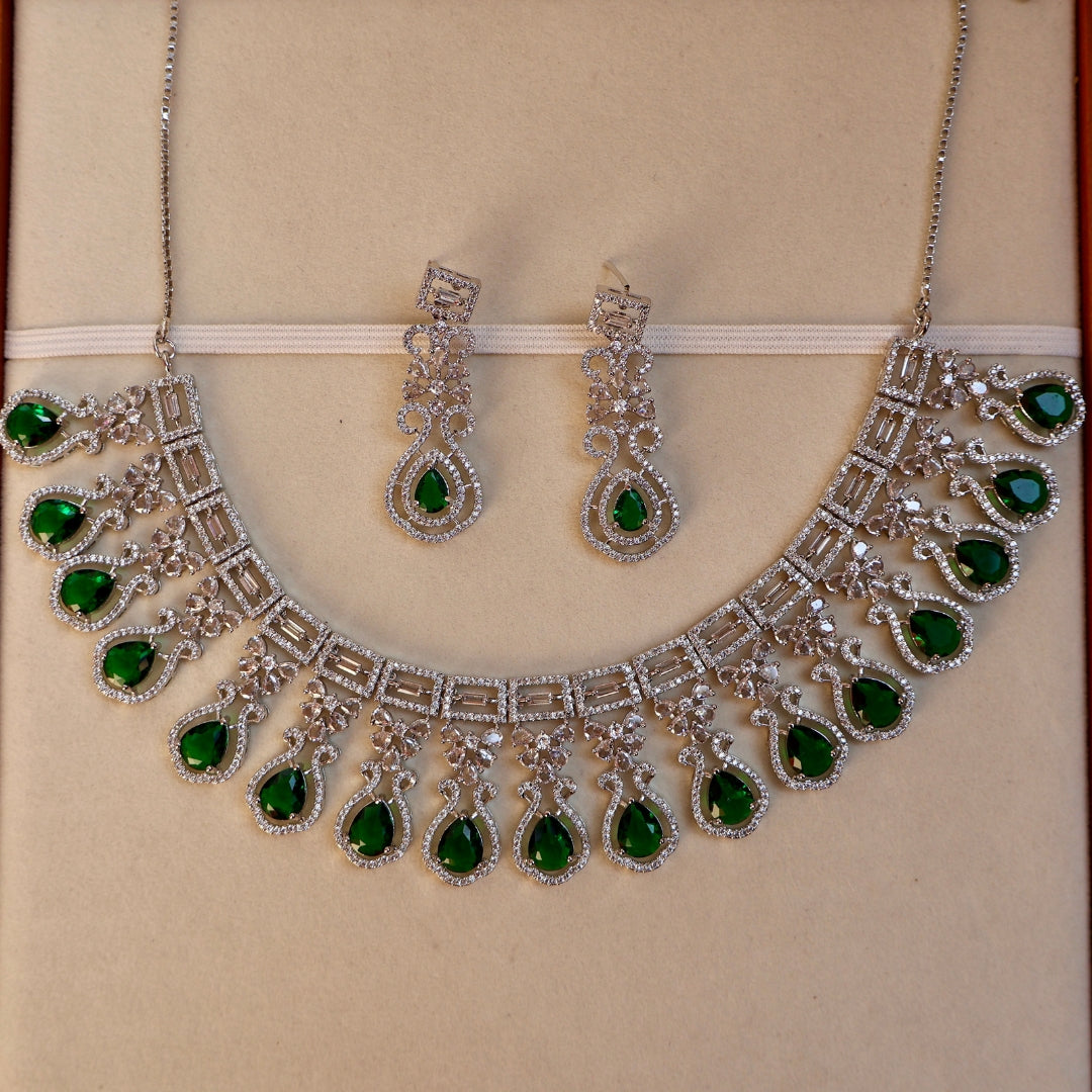 Jewelry set with necklace and earrings featuring green gemstones on a beige background