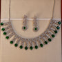 Jewelry set with necklace and earrings featuring green gemstones on a beige background
