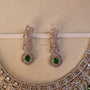 Pair of silver earrings with green gemstones on a beige background