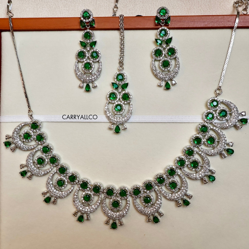 Jewelry set with necklace and earrings featuring green gemstones on a white background.