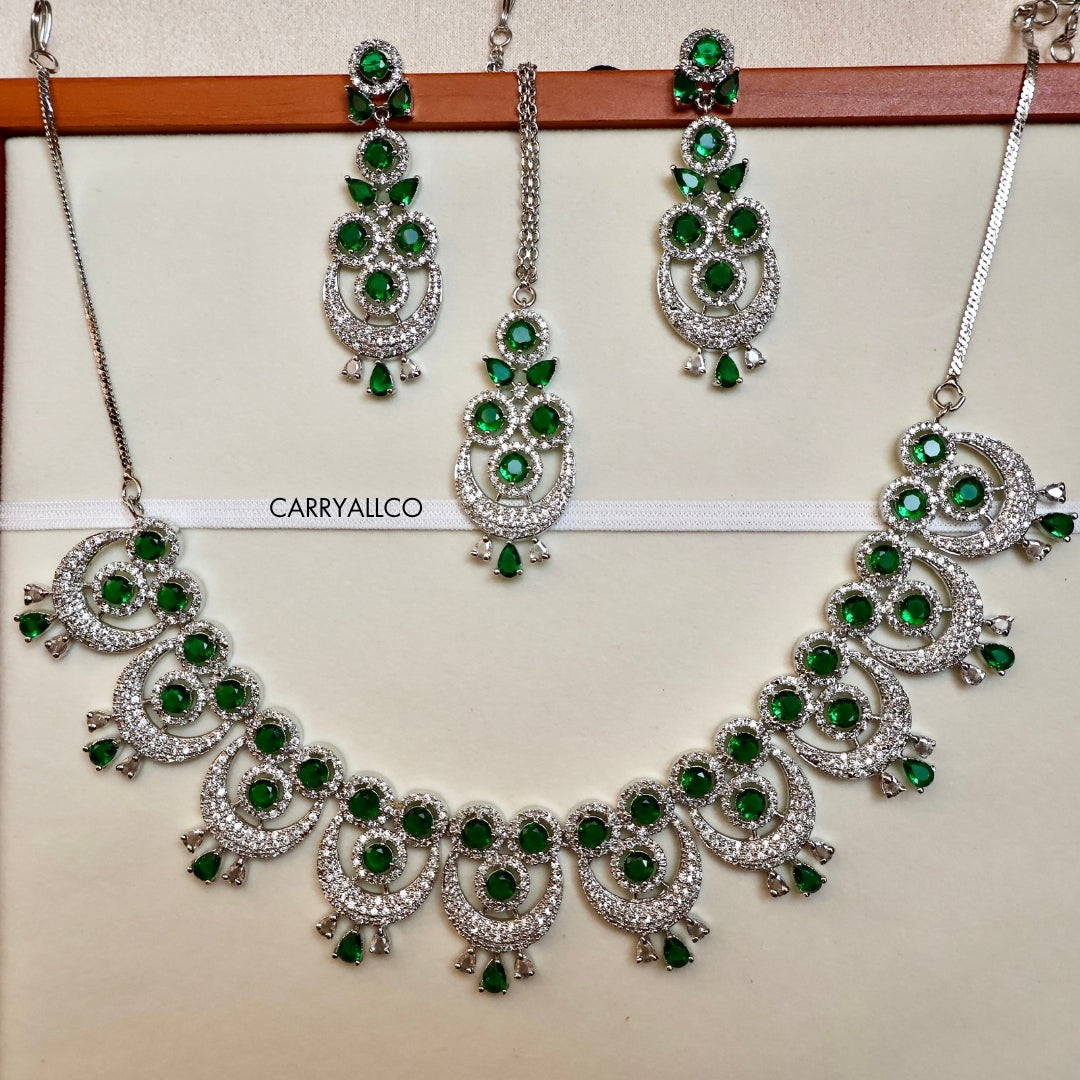 Jewelry set with necklace and earrings featuring green gemstones on a white background.