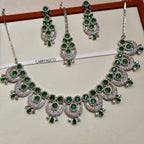 Jewelry set with green stones on a white and pink background