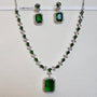 Jewelry set with necklace and earrings featuring green gemstones on a white background.