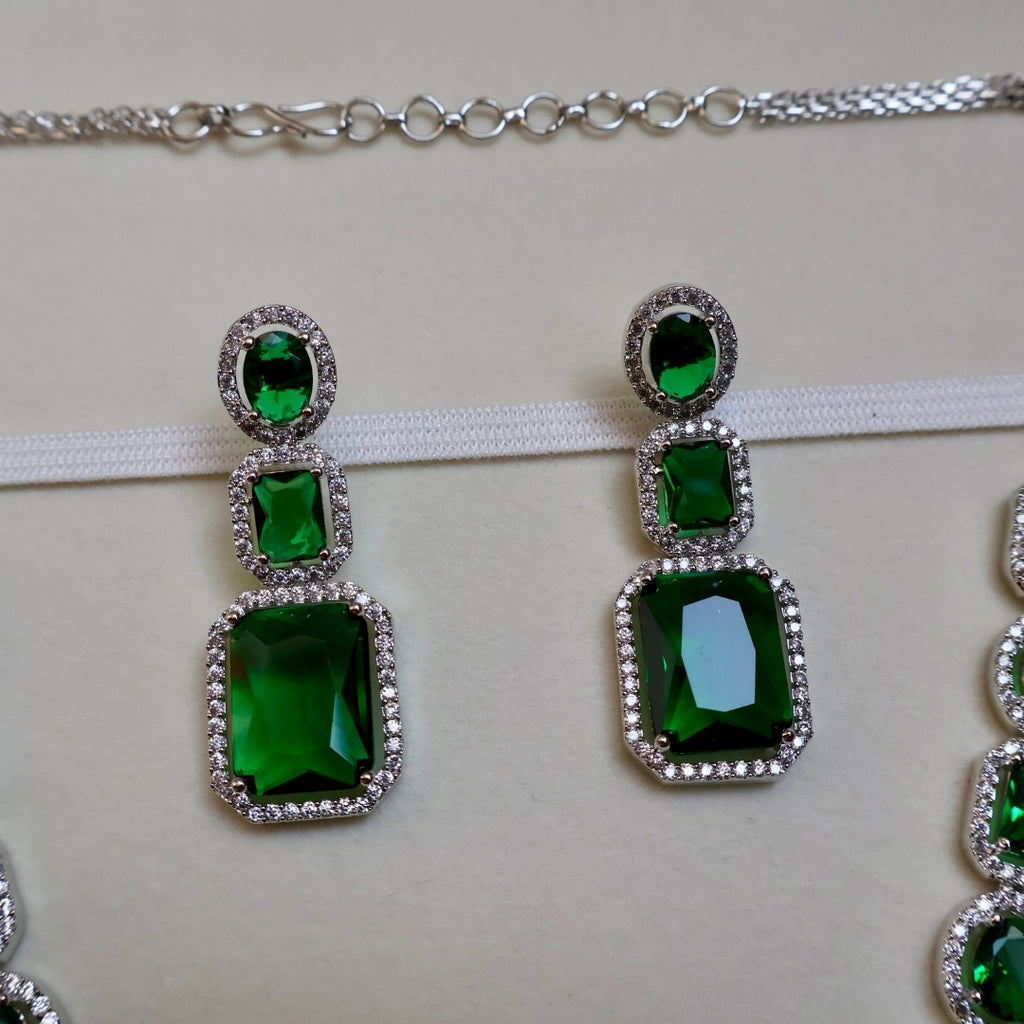 Green gemstone earrings with silver setting on a white background