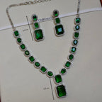 Jewelry set with green gemstones and silver accents on a white background