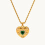 Gold heart-shaped necklace with a green gemstone on a white background